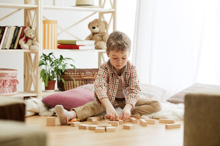 Bambino seduto gioca con mattoncini di legno